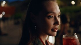 Carefree lady enjoy aperol cocktail standing night city close up. Relaxed attractive woman drinking sparkling wine at outdoors party celebrating weekend. Beautiful girl relaxing in evening town club. - Powered by Shutterstock - Get 15% off with code: PIKWIZARD15