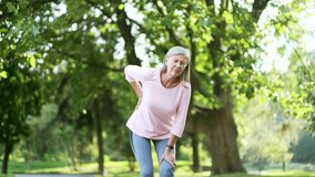 Senior gray haired woman suffering from back pain, sports injury, muscle spasm in urban city park. Sad mature old female having back flank ache and problem after workout outside, massaging a sore spot - Powered by Shutterstock - Get 15% off with code: PIKWIZARD15