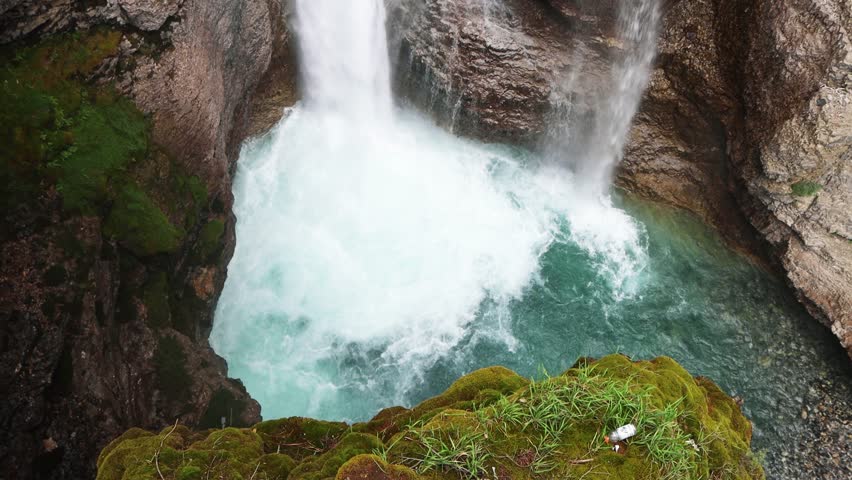 Turquoise water flowing through Johnstons Canyon, Banff National Park, Alberta, Canada. Waterfalls surrounded by green pine forests and mountain slopes.