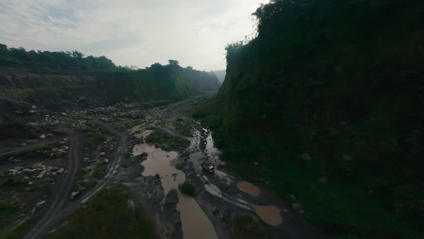 Fpv sport drone low flight in canyon dried river between covered green plants huge mountains formations asian country. Rocky sandy hill wall with gorge scenery picturesque aerial nature gloomy view 4k