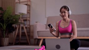 Young asian woman use laptop to listening music after watching fitness video to doing exercise