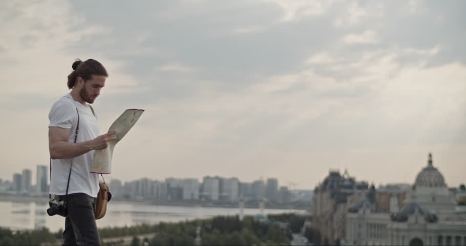 Male tourist standing on viewpoint with map planning route