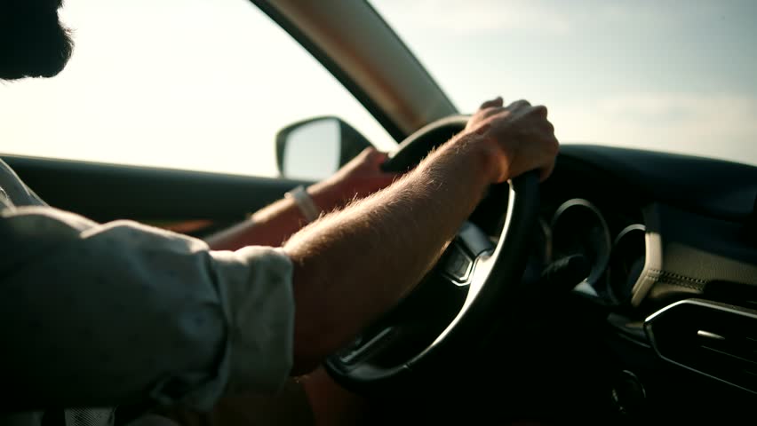 Male Driver Turning Steering Wheel In Car.Man Driving Auto And Using Controls In Car And Holding Wheel.Luxury SUV Driving.Businessman In Sunglasses Travelling On Automobile.Hand On Car Steering Wheels