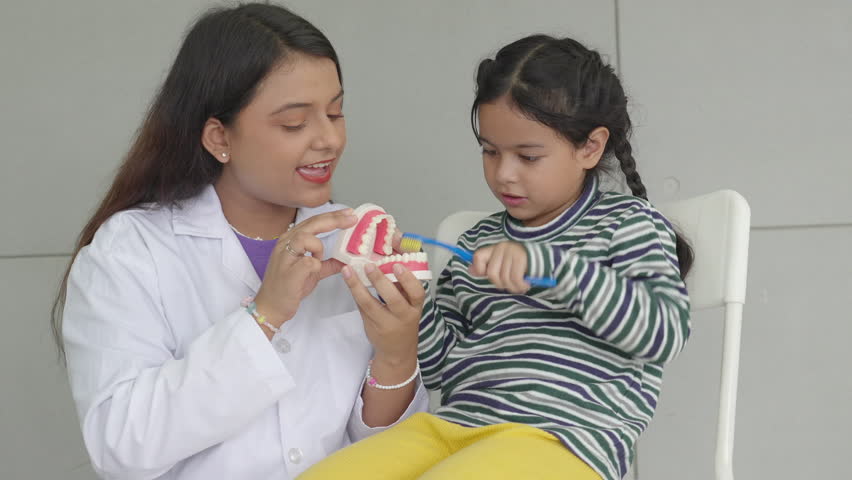 dentist teaching little girl how to cleaning teeth of dental jaw from model  Royalty-Free Stock Footage #1108398383