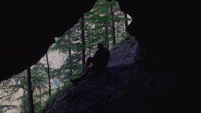 Hiker take a break, in a cave and read book outdoors, in nature