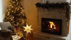 Atmospheric christmas eve at fireplace footage. Stylish christmas gifts, festive decorated tree with golden lights and cozy burning fireplace. Winter hygge