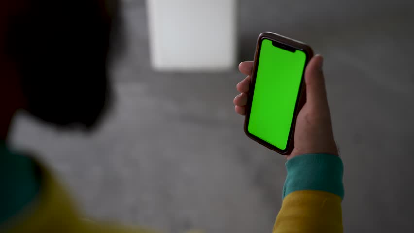 Man on his phone while sitting on a chair in different locations (Green Screen)