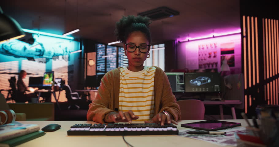 Zoom in: Stylish Young Black Woman Looking at Camera With Confusion While Working on Desktop Computer in Creative Office. Female Developer Trying to Fix a Bug, Unsure of the Source of the Issue Royalty-Free Stock Footage #1108413335