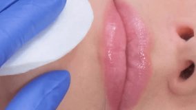 A young woman receives a botox injection in her lips. A woman in a beauty salon. Vertical video