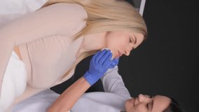A cosmetologist makes injections in the lips of a beautiful girl. Vertical video