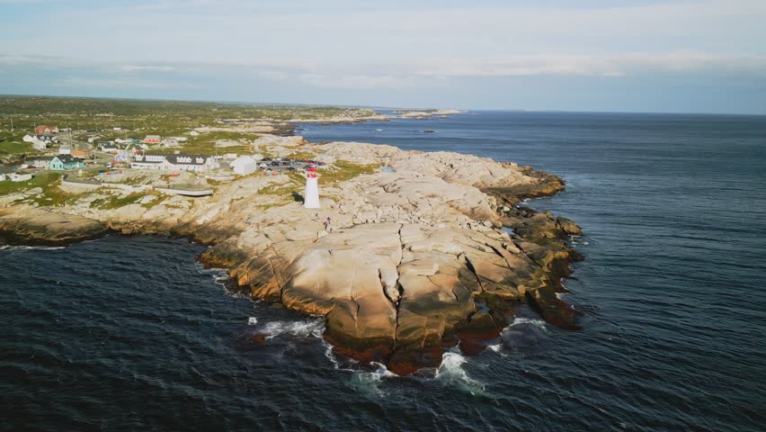 Cinematic Drone Shot of Peggy Cove Lighthouse at Sunset Atlantic Coastline Halifax Nova Scotia Canada Aerial View. An Old Lighthouse on a Rocky Ocean Shore with a Beautiful Evening Sunset.