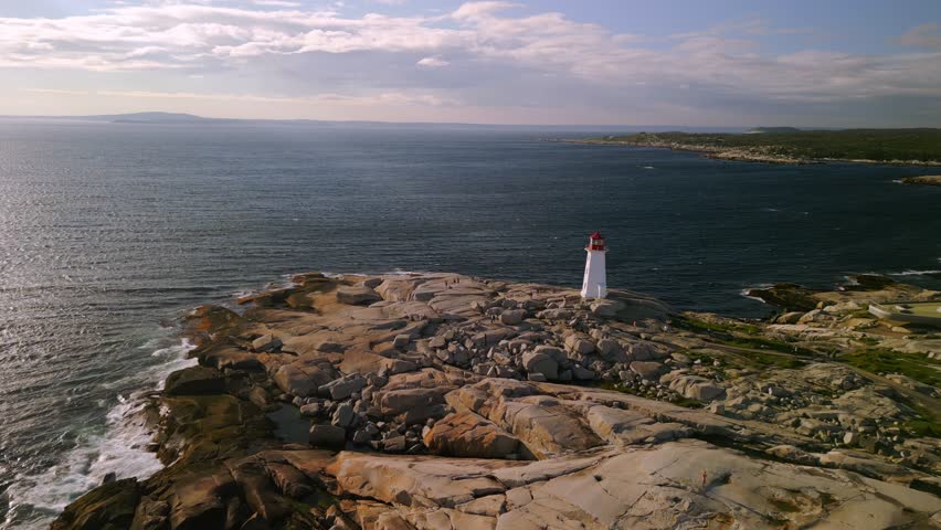 Aerial View of Peggy Cove Lighthouse at Sunset Atlantic Coastline Halifax Nova Scotia Canada Aerial View. An Old Lighthouse on a Rocky Ocean Shore with a Beautiful Evening Sunset. Royalty-Free Stock Footage #1108419105