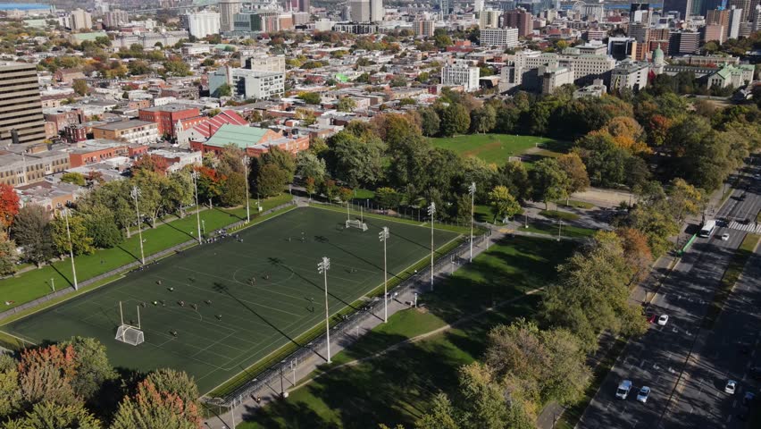 Aerial view of football field near houses in old Montreal district, Canada at autumn. View of Mont Royal mountain park.  Drone footage  on sunset.