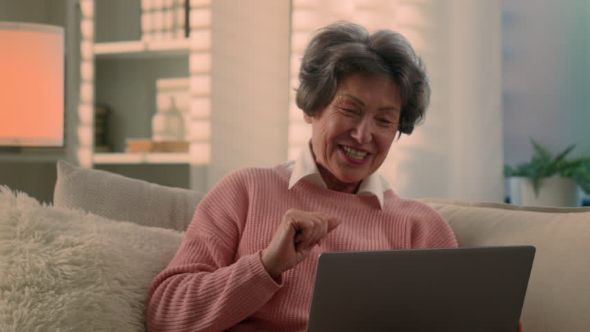 Carefree joyful smiling retired Caucasian happy cheerful old woman senior lady mature retirement elderly female smile talking pleasant conversation online chat video call with laptop at home couch Royalty-Free Stock Footage #1108419287