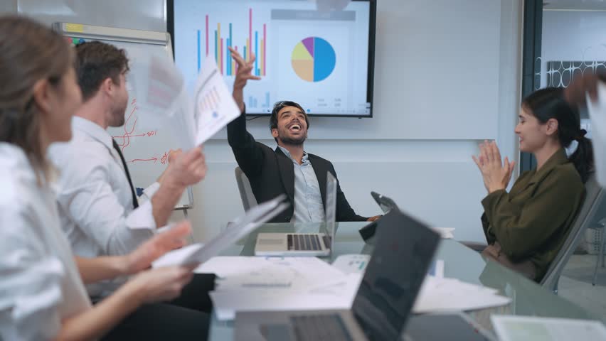 Happy team of business people throwing papers in the air and clapping hands after finish meeting or success business deal in boardroom at office. Celebrating by throwing business papers