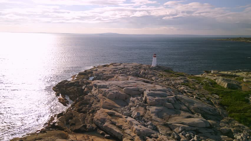 Cinematic Drone Shot on Peggy Cove Lighthouse Nova Scotia, Halifax, Canada. Cinematic Drone Shot of a Beautiful Lighthouse at Sunset with Stormy Wind and Waves on a Rocky Coastline.