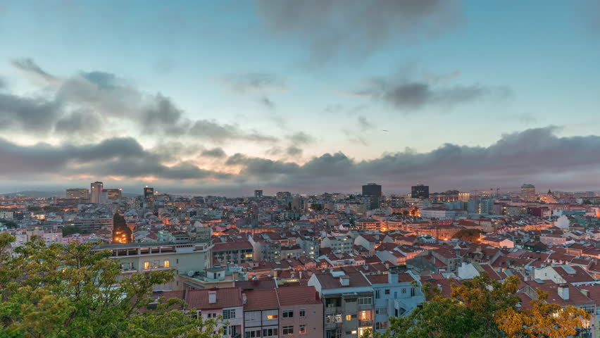 Panorama showing aerial view of downtown of Lisbon day to night transition timelapse, Portugal. Red roofs of typical houses in old town skyline. Historical district after sunset in capital city