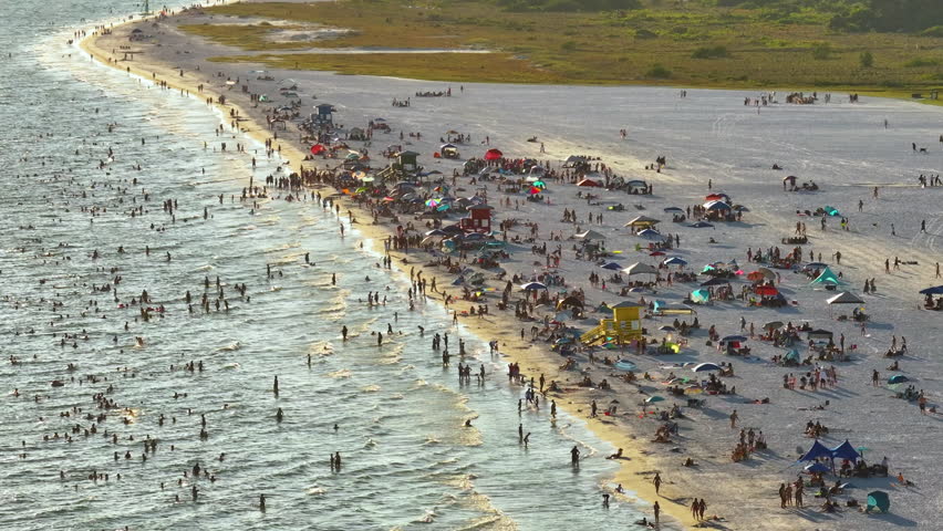 Famous Siesta Key beach with soft white sand in Sarasota, USA. Many people enjoing vacation time bathing in warm gulf water and tanning under hot Florida sun at sunset