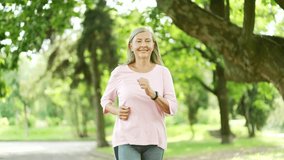 Senior active gray haired female runner jogging in urban city park and looking smart watch. Mature old fit woman using fitness tracker and checking result. Elderly sportswoman on training in nature - Powered by Shutterstock - Get 15% off with code: PIKWIZARD15