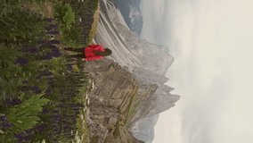 Aerial vertical shot hiker woman hiking epic mountain rock peak of Seceda Dolomites. Travel exploring Alps Dolomites Italy nature outdoor on a dramatic cloudy day