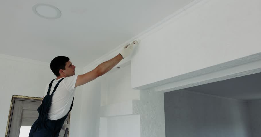 man painting wall in white color with roller