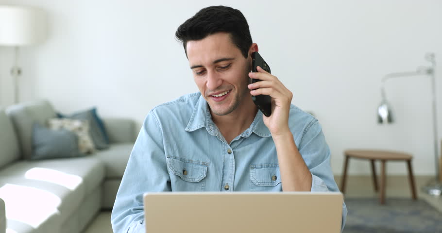 Young man holding cellphone talks to customer services makes order sit at desk with laptop, calling by business, discuss purchase, communicates remotely using modern wireless technologies, phonecall Royalty-Free Stock Footage #1108437813