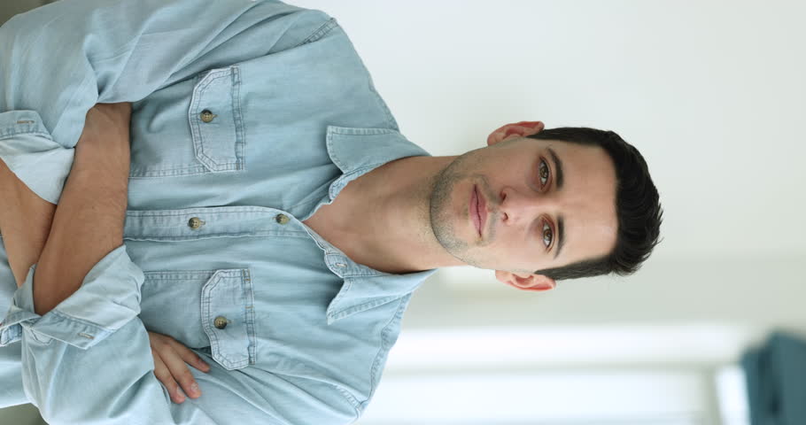 Handsome Hispanic man in casual blue shirt posing indoor with arms-crossed on chest. Vertical portrait attractive positive millennial single guy. Professional occupation, business success, achievement Royalty-Free Stock Footage #1108437863