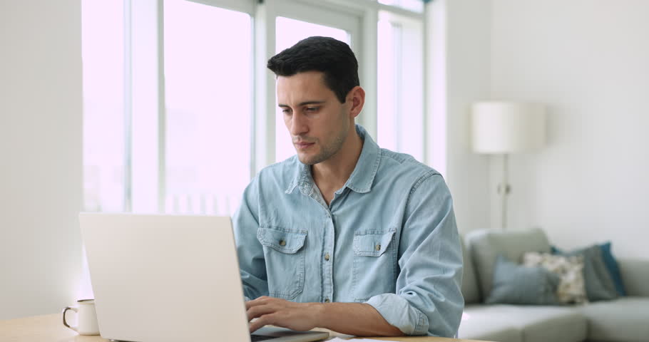 Handsome smiling Hispanic man working or studying using laptop, read good news in e-mail, check correspondence feels overjoyed celebrate great business or job opportunity sit at desk at home office Royalty-Free Stock Footage #1108437877