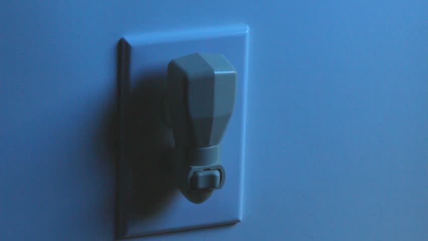 A women's hand flips a light switch on the nightlight to turn it on, and then