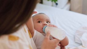 Asian mother holding and feeding baby from a milk bottle. close-up of a cute newborn baby being fed by her mother using a bottle. concept: Mother's day, relation mother and kid. - Powered by Shutterstock - Get 15% off with code: PIKWIZARD15