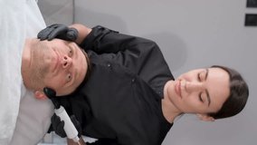 Vertical video of a beautician using a radio frequency lifting device on a man's face. Vertical 