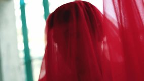 An artistic close-up of a person's face completely obscured by a flowing, sheer red fabric. The figure moves, causing the fabric to float and swirl, creating a mysterious and abstract visual. - Powered by Shutterstock - Get 15% off with code: PIKWIZARD15