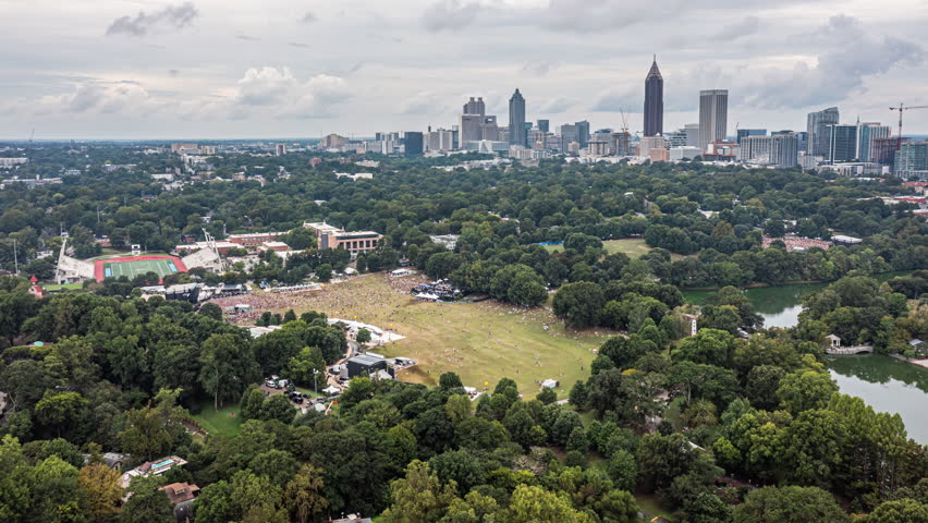 Atlanta Georgia Aerial v731 drone hyperlapse flying across crowded music festival at midtown piedmont park with downtown cityscape in the background - September 2021