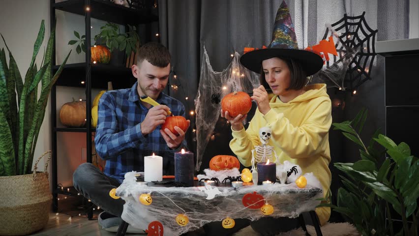 Happy halloween. Happy joyful couple friends paint orange pumpkins at Halloween party. Trick or treat. Traditional Halloween symbols. Celebration of Halloween | Shutterstock HD Video #1108460159