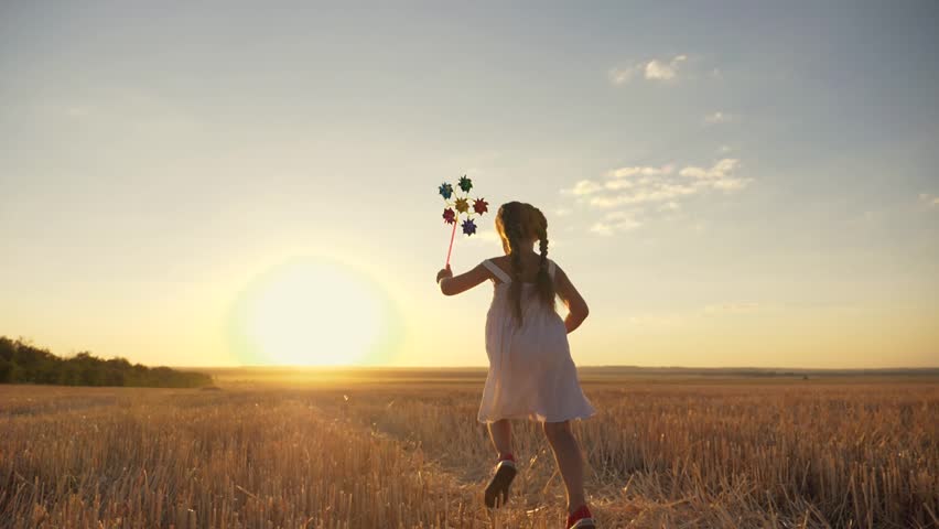 Happy girl runs across field at sunset with windmill in her hands. Silhouette of joyful girl holding wind toy. child enjoys fresh air. fun game in wind in field. Happy child runs at sunset.Wind toy Royalty-Free Stock Footage #1108461263