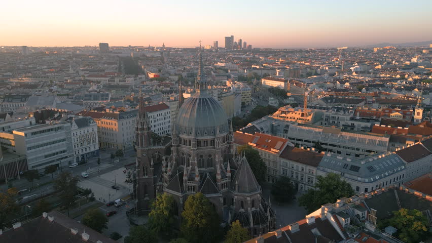 Austria Vienna skyline aerial view drone footage at sunrise morning light, drone fly over city downtown, church Maria vom Siege Vienna city skyline panoramic viewtraffic and skyscrapers in front.