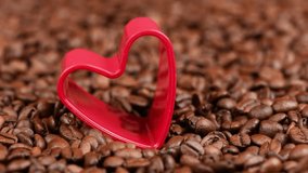 Red heart in roasted coffee beans background. 4K UHD video footage 3840X2160.