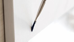 Vertical video. Painting process. Art school. Set of 2 closeup paintbrush with blue color watercolor paint creating artwork inspiration on white fabric canvas free space.