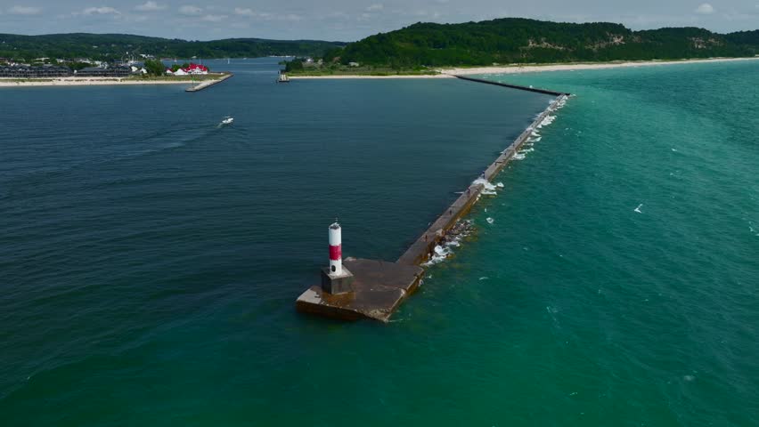 Aerial Drone footage of the Lake Michigan Shoreline in Frankfort. A beautiful sunny summer day with sand dunes, waves, boats, and lighthouses visible.