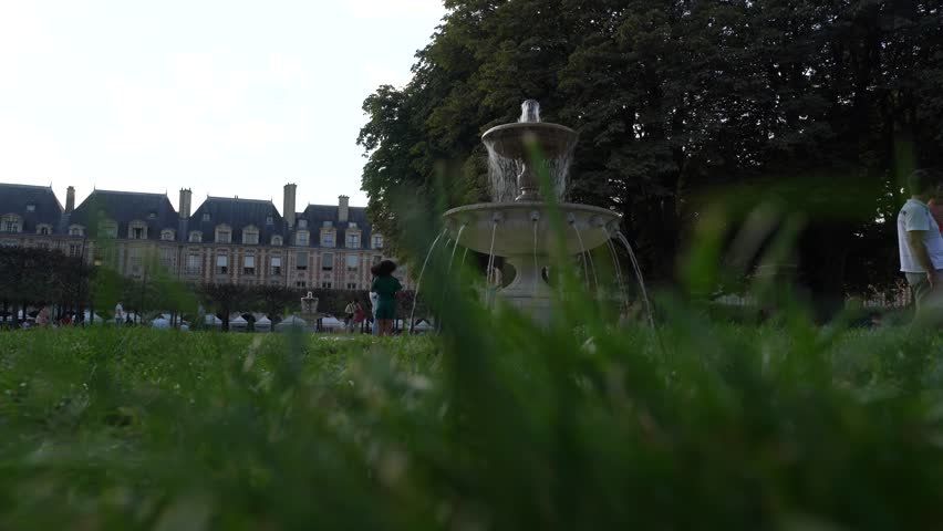 Paris france 09 09 2023 : Place des Vosges , famous garden and square in Paris , close up grass and families enjoying the warm weather in the background
