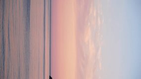 Vertical Aerial panoramic view of beautiful sunset above sea. Beautiful seascape. Sun glare, small waves on the water surface. Evening. Horizon. Nobody. No people. Never-ending beauty of nature.