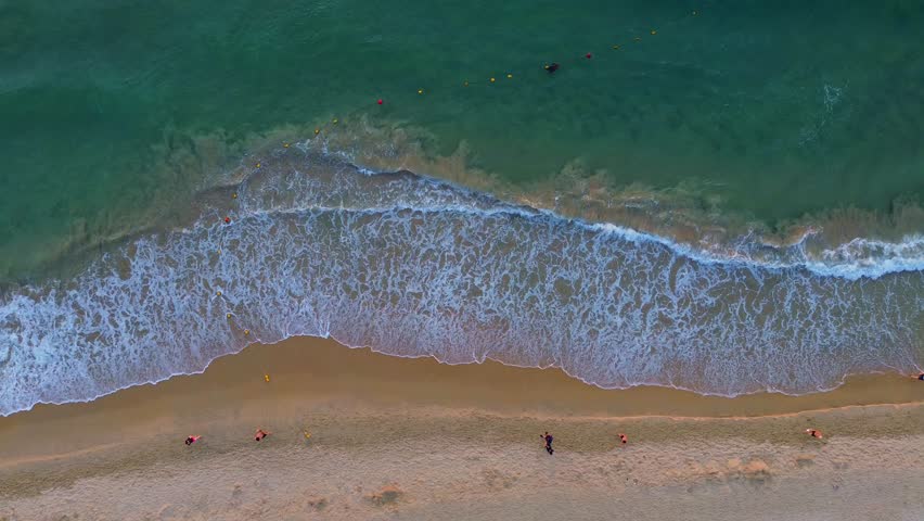 Landscape of My Khe beach, Da Nang, Vietnam with pedestrians exercising and waves at dawn filmed from above.  Beach and people.  Travel concept, ocean sea background. Royalty-Free Stock Footage #1108486597