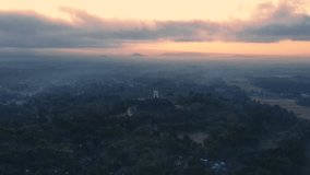 Reveal drone shot of Borobudur Temple with magical light of sunrise in misty morning. the land still dark with an orange sky. Ancient Buddhist Temple. Magelang, Indonesia - 4K drone shot