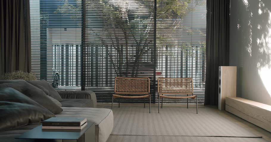 living room with panoramic window with blinds, comfortable couch, rattan armchairs and rug on floor in apartment with modern interior. contemporary design in cottage house.