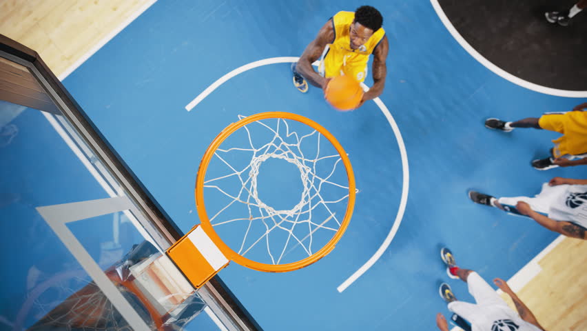 Slow Motion Cinematic Replay of Basketball Action for Live TV Channel Playback: Top Down Zoom Out Footage of an African Yellow Team Player Scores a Powerful Slam Dunk Goal and Hangs on the Hoop Royalty-Free Stock Footage #1108499969