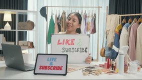 Young Asia lady beauty blogger wear crop top hold whiteboard smile looking at camera live stream talk follower introduce her chanel ask audience like subscribe share her chanel at house studio.