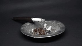 video of cigarette smoke in an iron ashtray on a black background