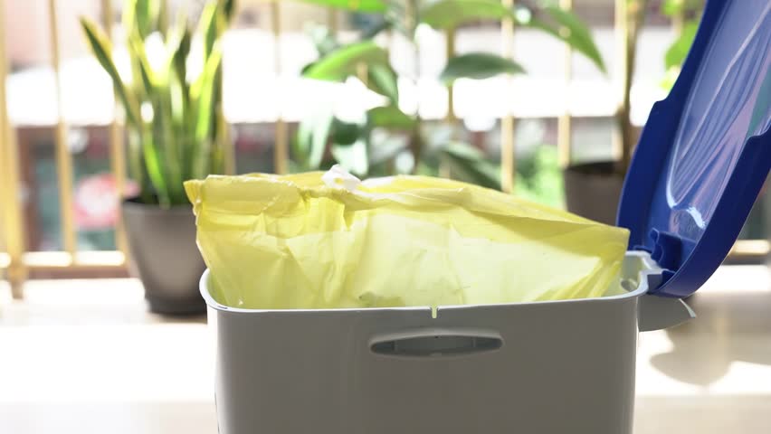 A man takes out a yellow bag of waste from a trash can. | Shutterstock HD Video #1108508725