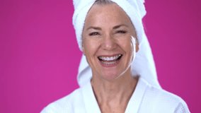 POV of smiling mature woman talking to camera holding phone recording vlog while at spa wearing bath robe. Gray-haired senior woman video calling in online chat using smartphone self portrait.