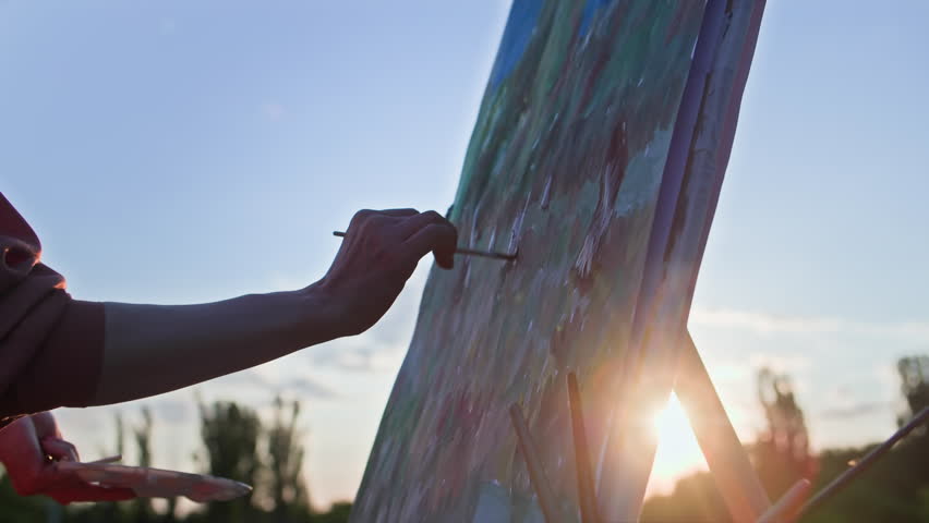 art therapy, a young woman uses brushes and beautifully draws a creative picture in nature in an outdoor park, outline plan